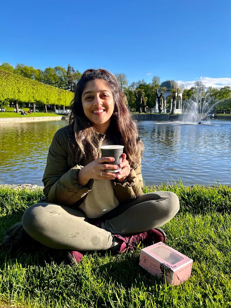 Young woman drinking a coffee in front of a fountain
