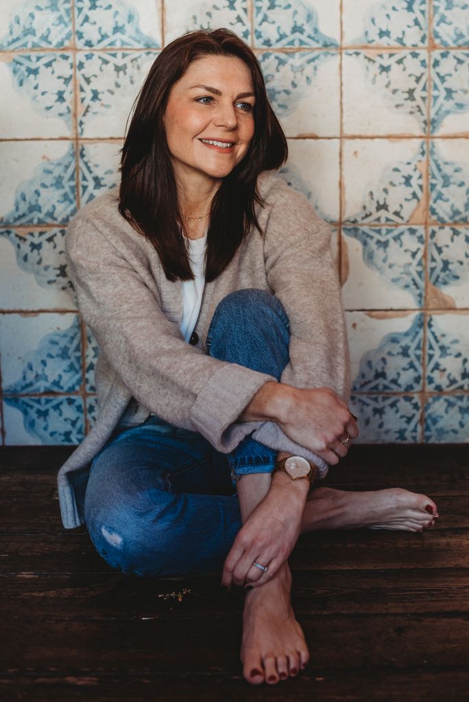 Woman sitting on the ground in jeans against pretty tiles