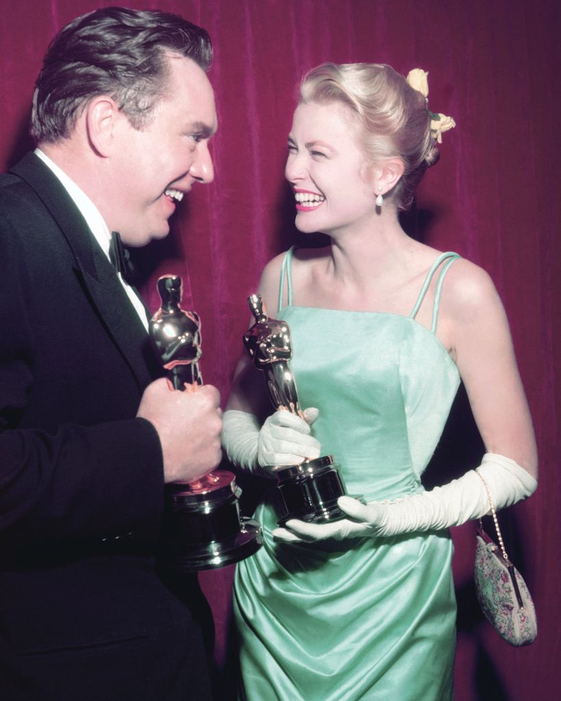 Edmond O'Brien and Grace Kelly smiling holding oscars