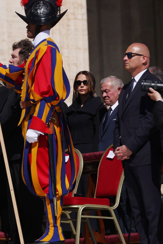 Queen Rania Of Jordan and King Abdullah II among people in black outfits