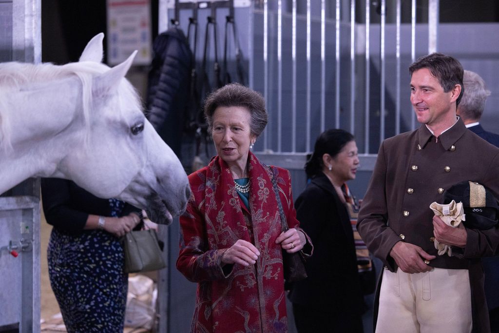 The Princess Royal in red coat in stables