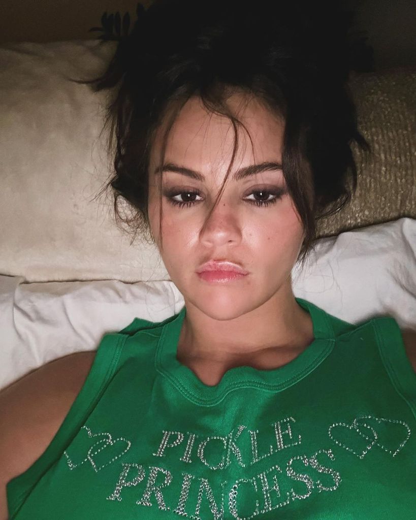 Selena Gomez lying in bed in a green top