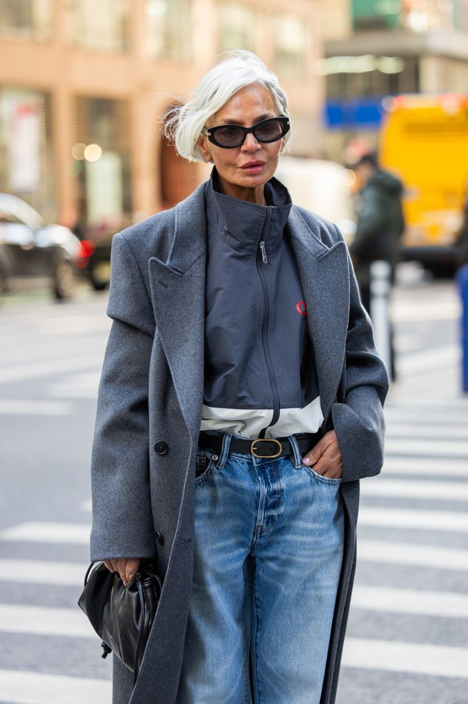Grece Ghanem wears grey coat, black bag, jeans, zipper outside Calvin Klein on February 07, 2025 in New York City.