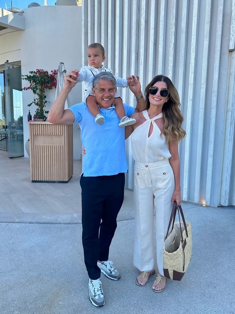 Karren brady beside husband with baby on shoulders