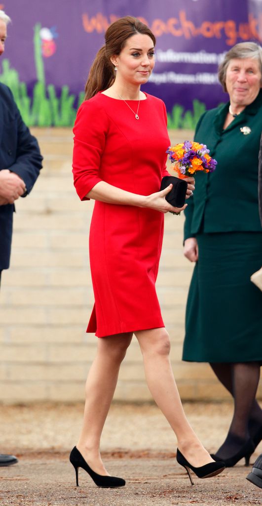 Kate in red dress with black heels holding flowers