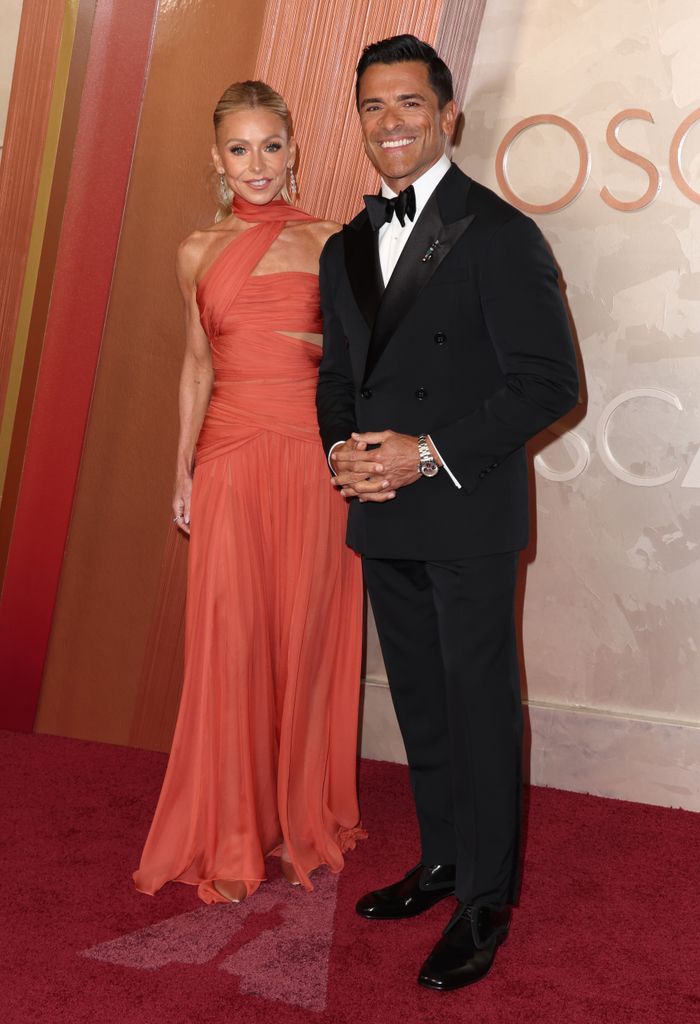 Kelly Ripa in an orange dress and Mark Consuelos in a tuxedo pose on the red carpet of the 97th Annual Academy Awards, Arrivals, Los Angeles, California, USA - 02 Mar 2025