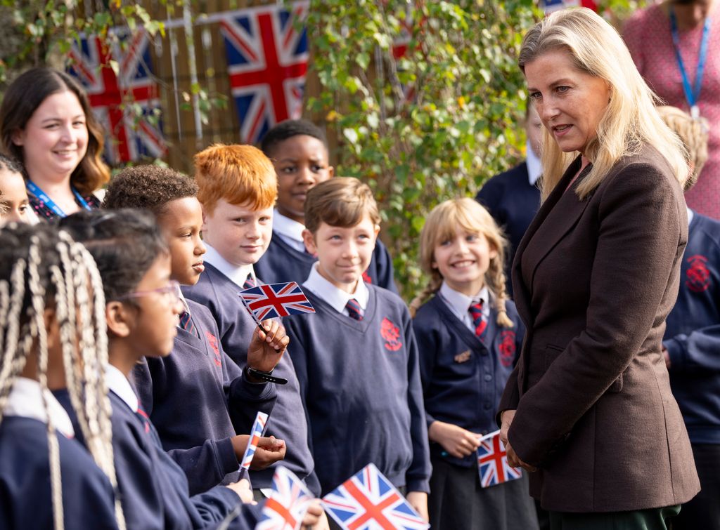 Sophie in brown blazer talking to school kids