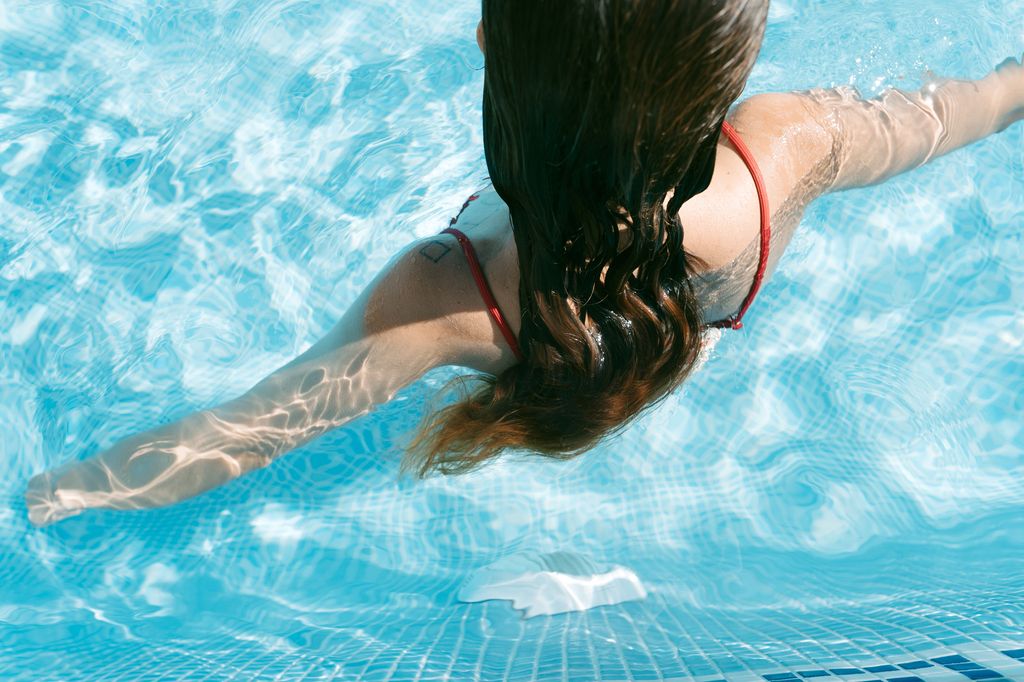 High angle view of a young caucasian woman with a red bikini relaxing in pool. Summer time.