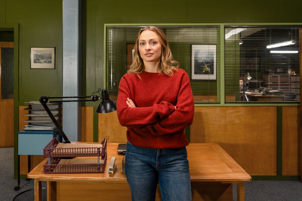 blonde woman in red jumper standing in office