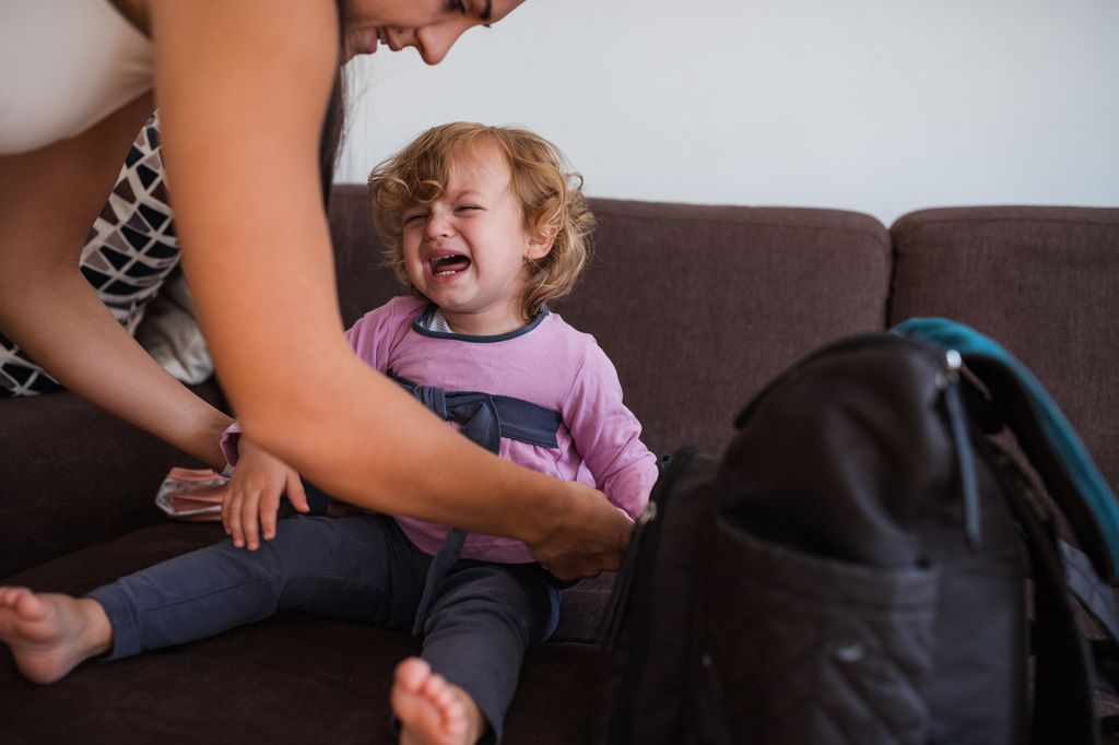 Woman trying to dress a child who is crying