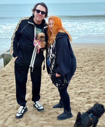 jonathan ross and wife jane goldman wearing casual clothes posing with pet dogs by sea