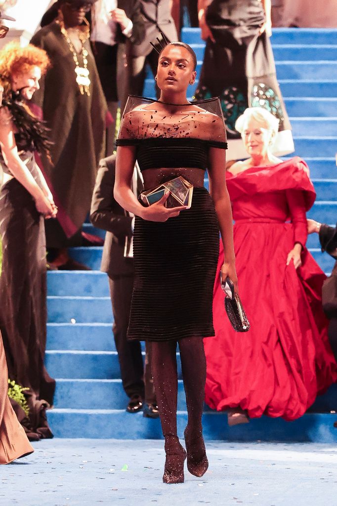 Simone Ashley wearing a black sheer cocktail dress by Jean Paul Gaultier with heart bag