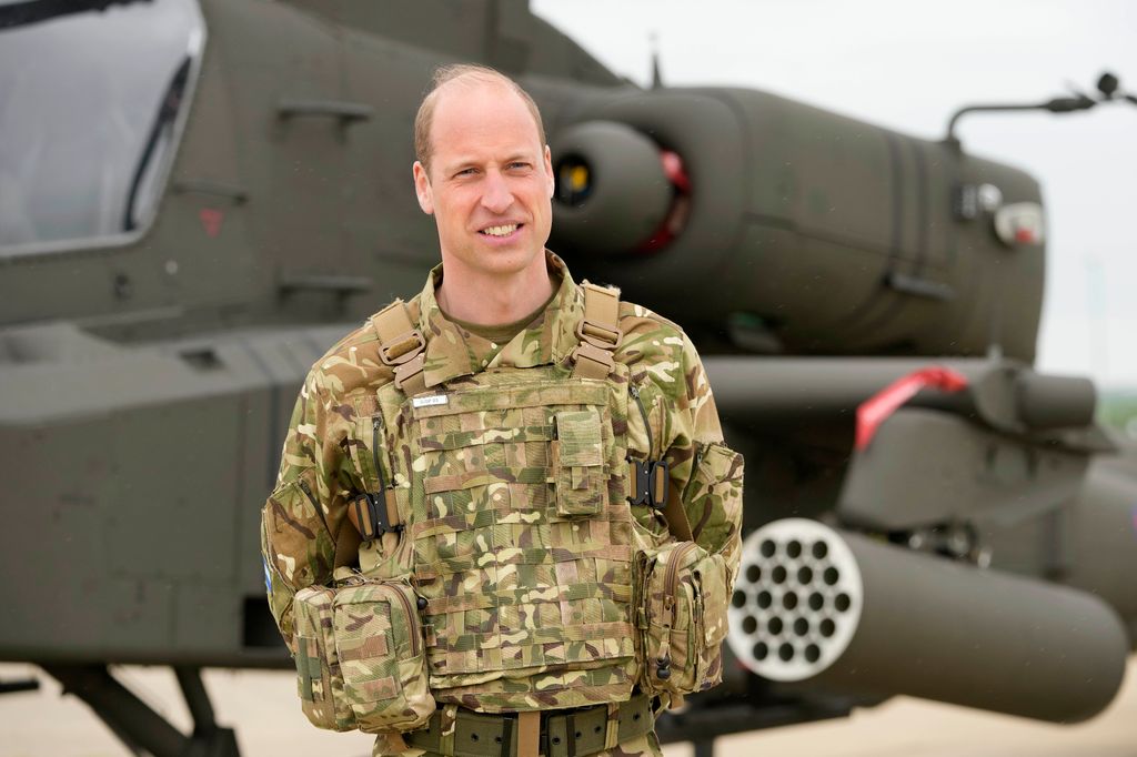 Prince William standing in front of an Apache helicopter 
