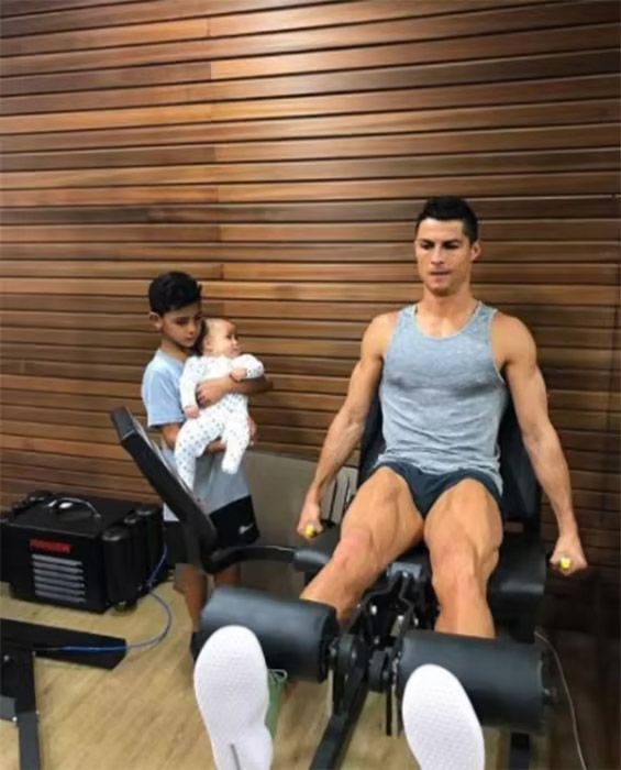 cristiano ronaldo on leg gym machine with two kids watching 