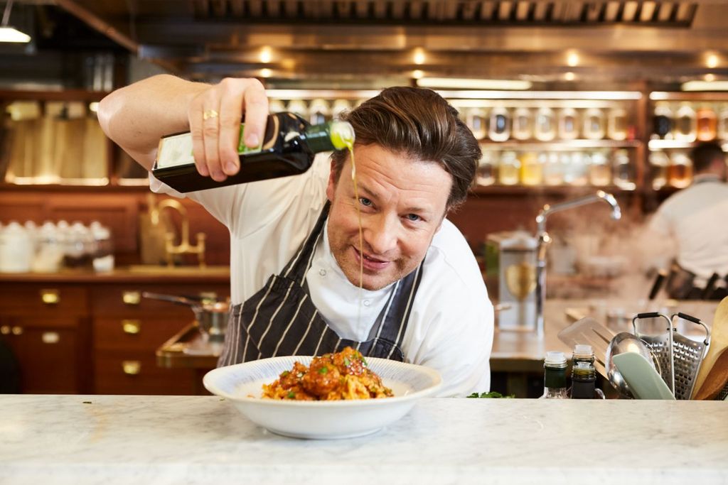 Jamie oliver pouring oil into bowl of pasta