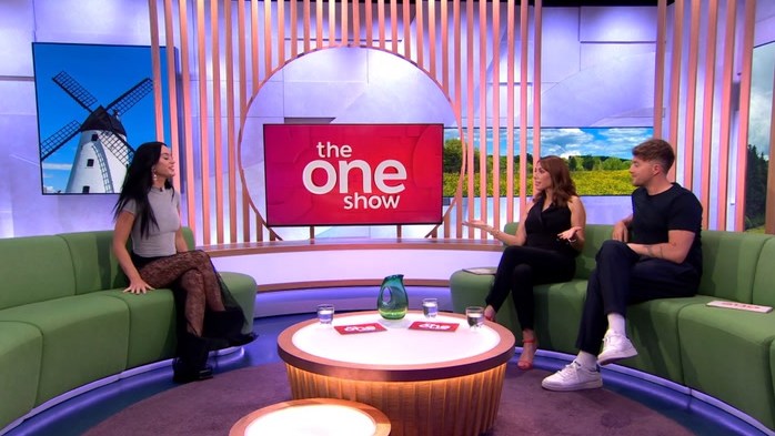woman being interviewed by man and woman on green sofas in studio