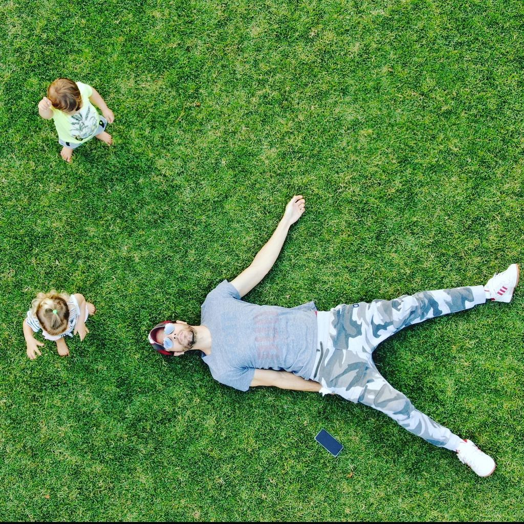 Enrique laying down on grass with kids