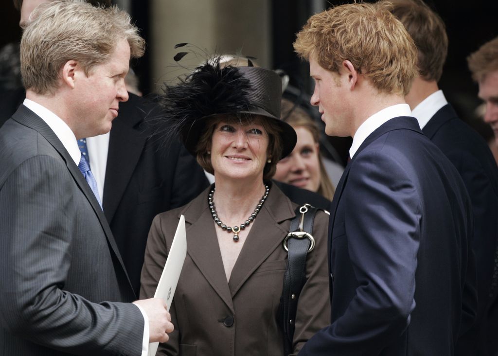 Lady Sarah McCorquodale  in a brown suit and black feathered hat, smiling at Prince Harry who is talking to Earl Spencer