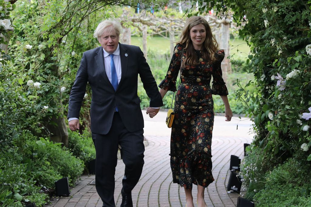  Boris Johnson and his wife Carrie Johnson walking through a floral arch in a garden