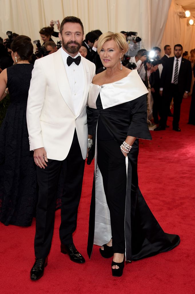 Hugh Jackman in a white suit jacket and Deborra-Lee Furness in a black and white jumpsuit on the red carpet