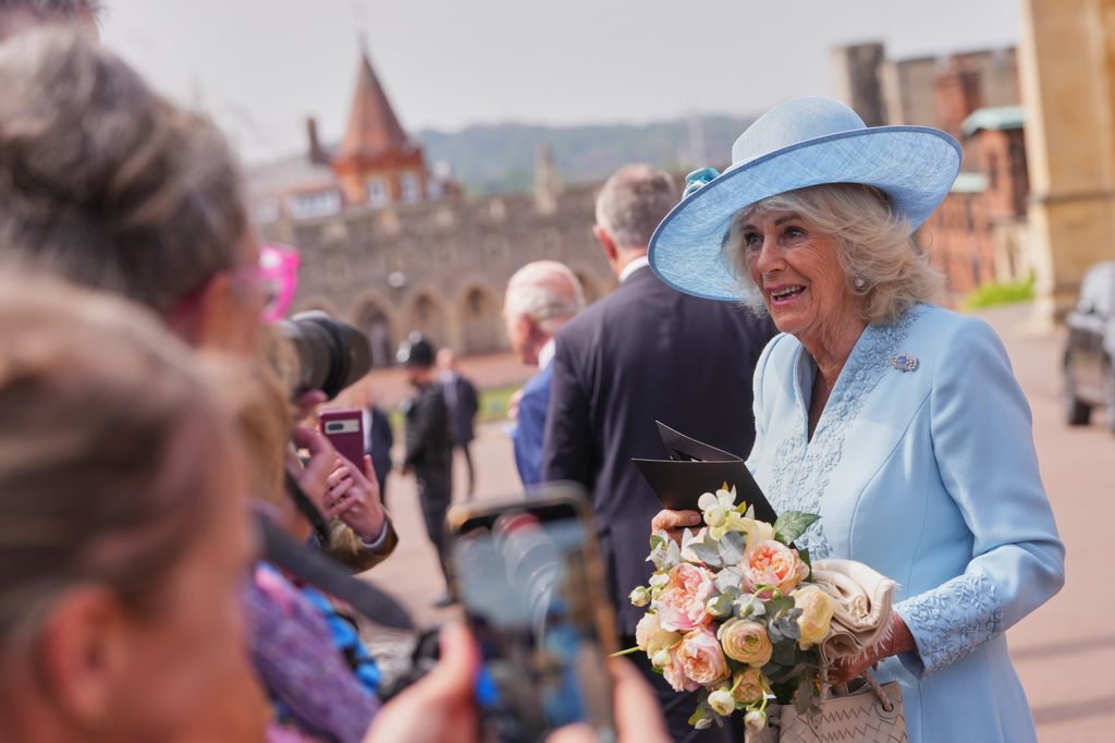 Queen Camilla holding flowers as she meets members of the public