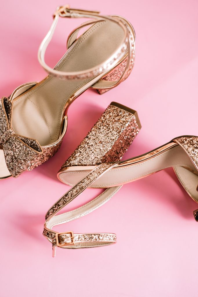 Golden womens shoes with heels and sequins on pink background