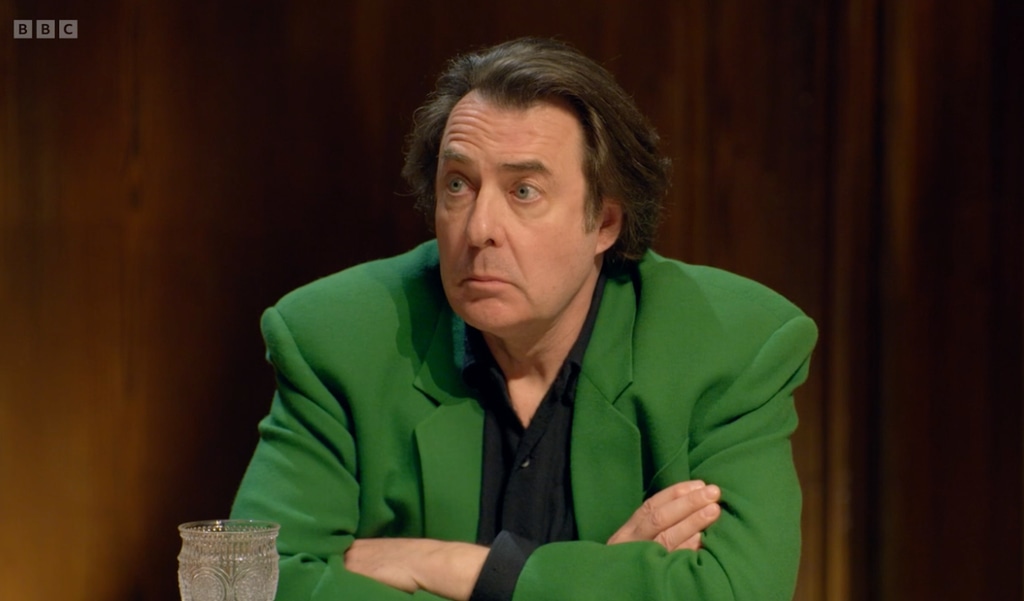 man in green blazer sitting at table 