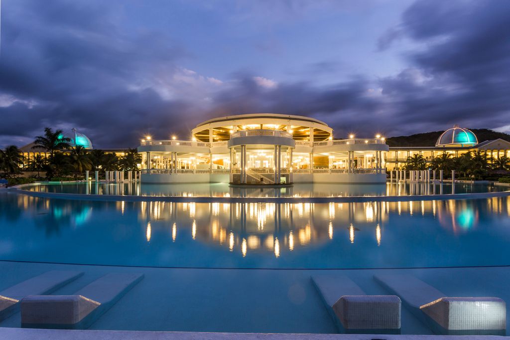 swimming pool at dusk, with a building in the middle with lights on