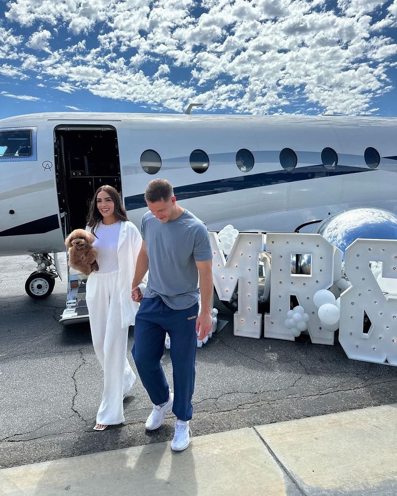 Oliva Culpo and Christian McCaffrey standing in front of a private jet