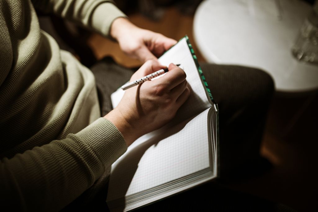 Close-up image focuses on a man making notes in a journal