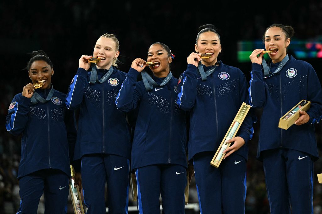 US' Simone Biles (L) and teammates pose with the gold medal during the podium ceremony for the artistic gymnastics women's team final during the Paris 2024 Olympic Games