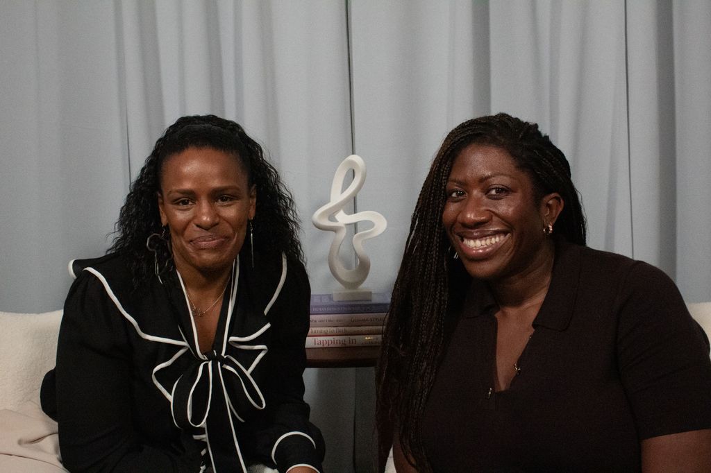Two black women smiling in a podcast studio