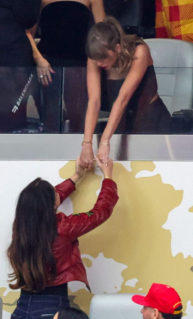 Lana and Taylor holding hands at the super bowl