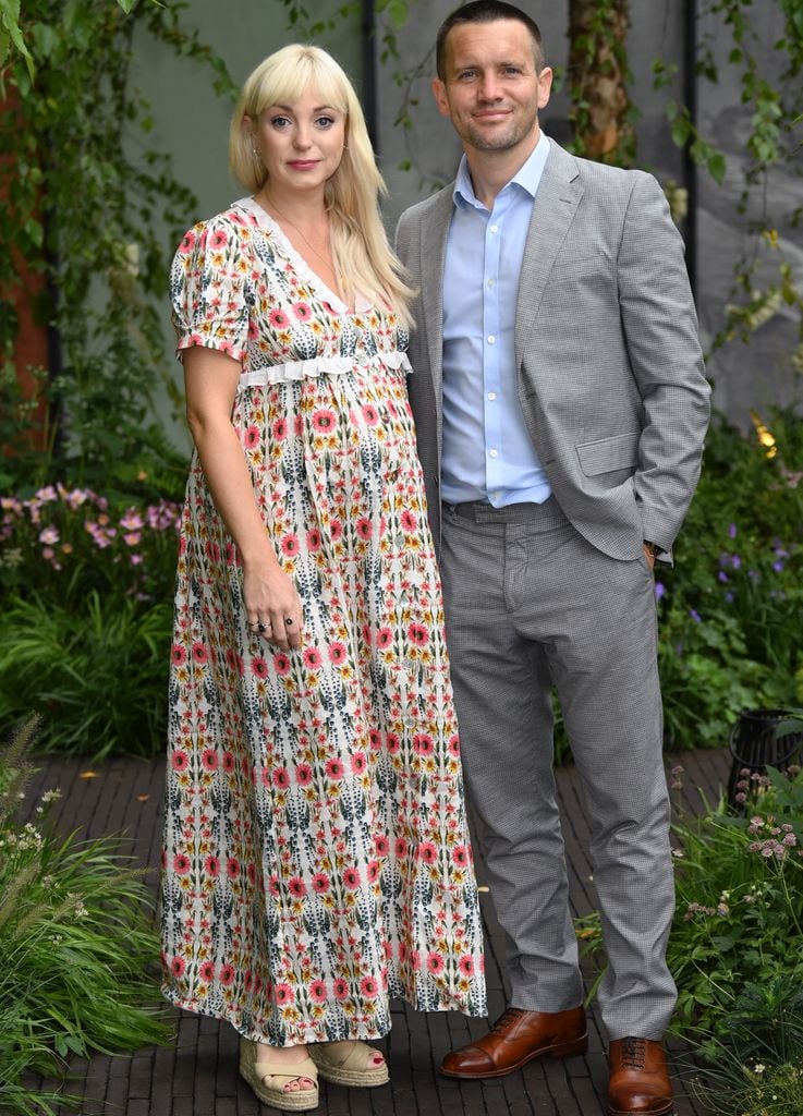 Helen George in a floral dress posing outside with suit-clad Jack Ashton