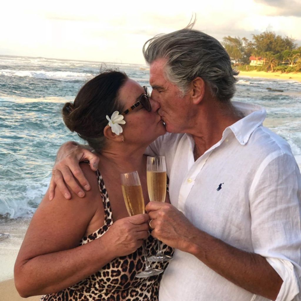 Pierce Brosnan kissing his wife Keeley with the ocean behind them