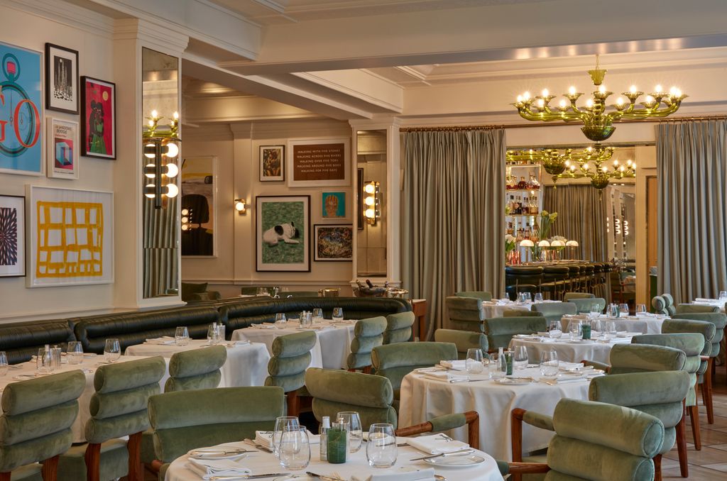 restaurant with green chair, tables with white tablecloth and artwork on the walls