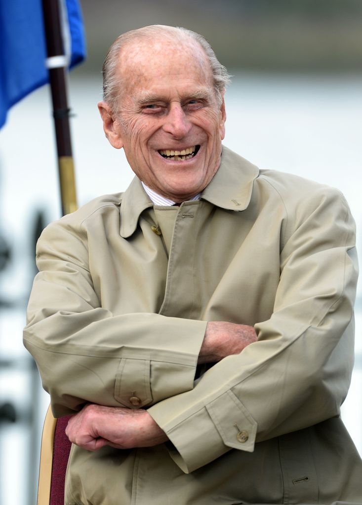 Prince Philip laughing whilst wearing a beige mac