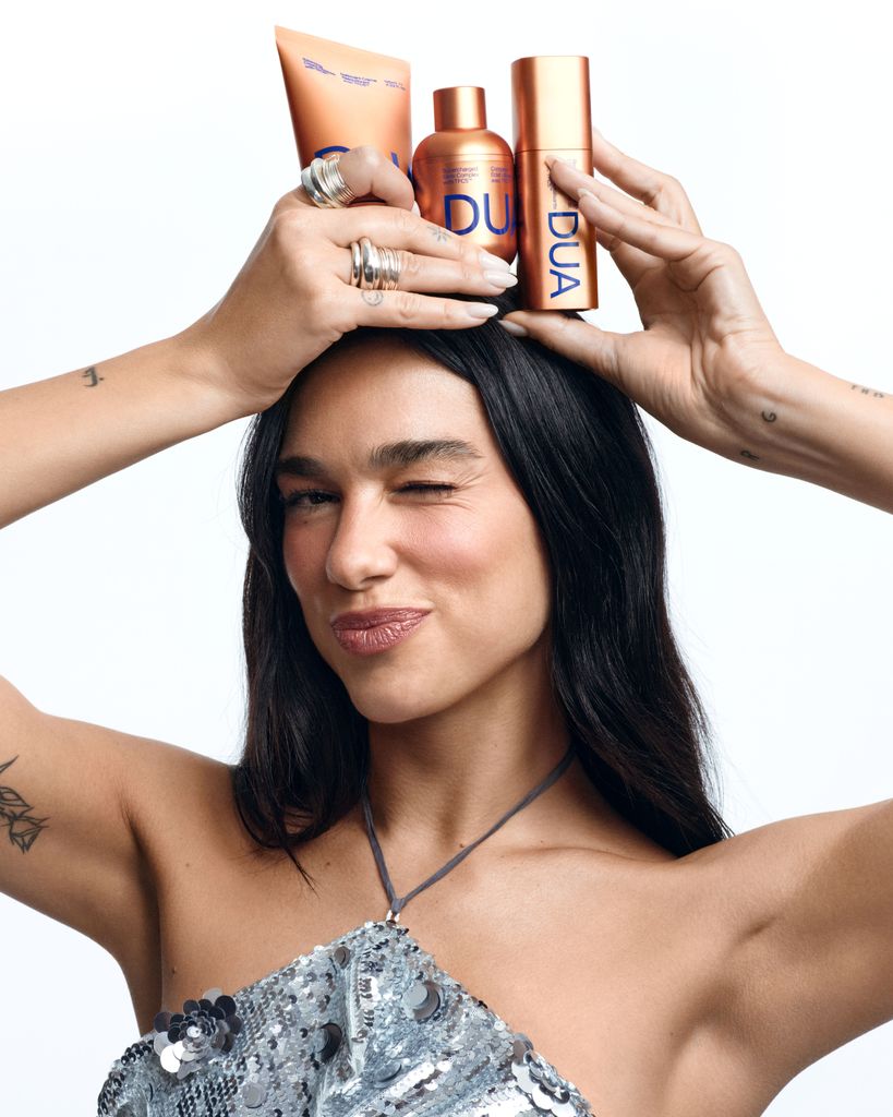 Dua Lipa holding her skincare range above her head