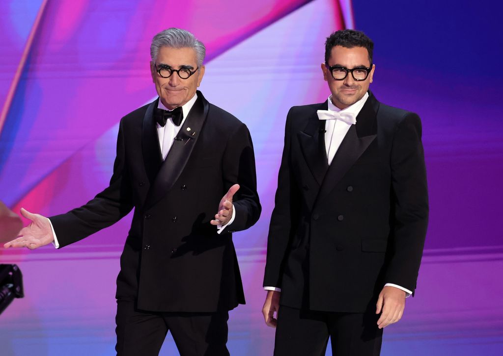 Eugene Levy and Dan Levy on stage in black suits and bow ties 