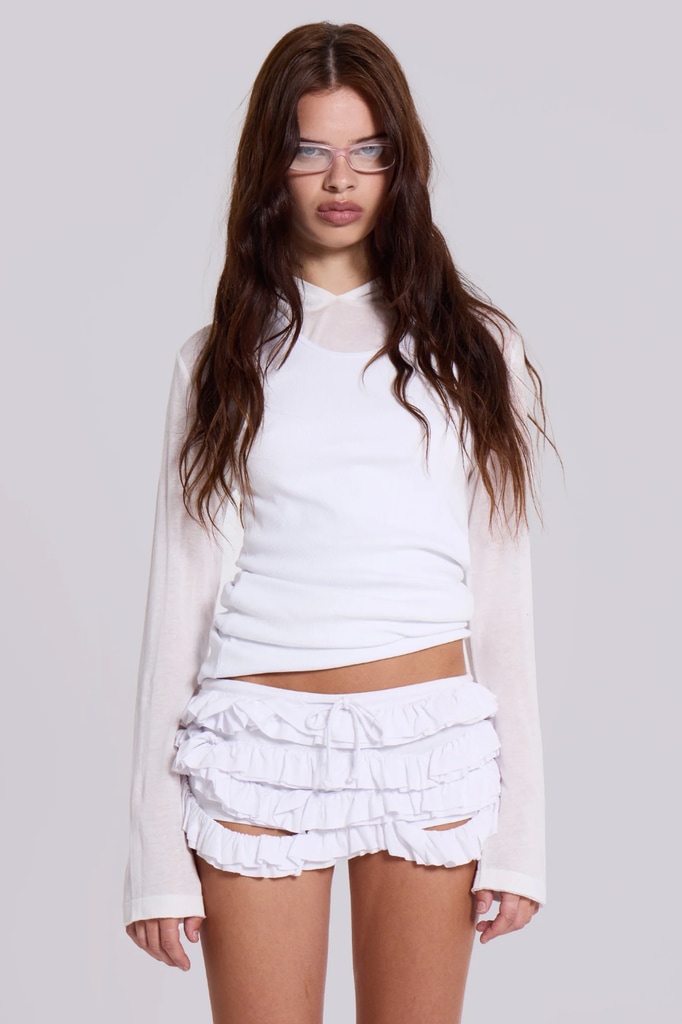 A model poses in a white shirt and ruffle shorts