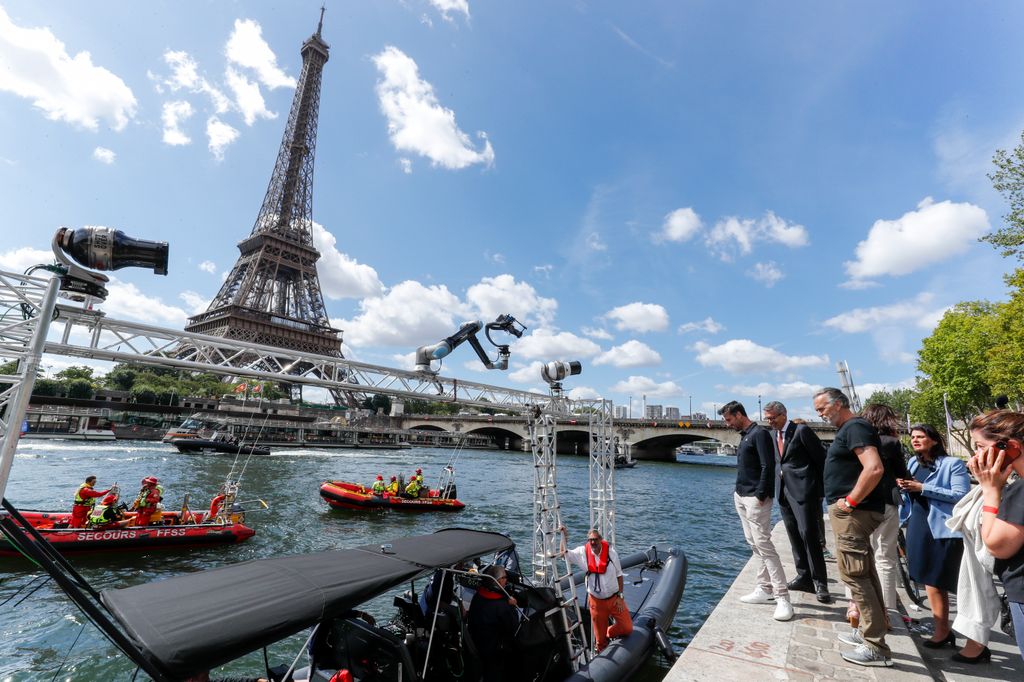 A group of people on the side of the River Seine with the Eiffel Tower in the background