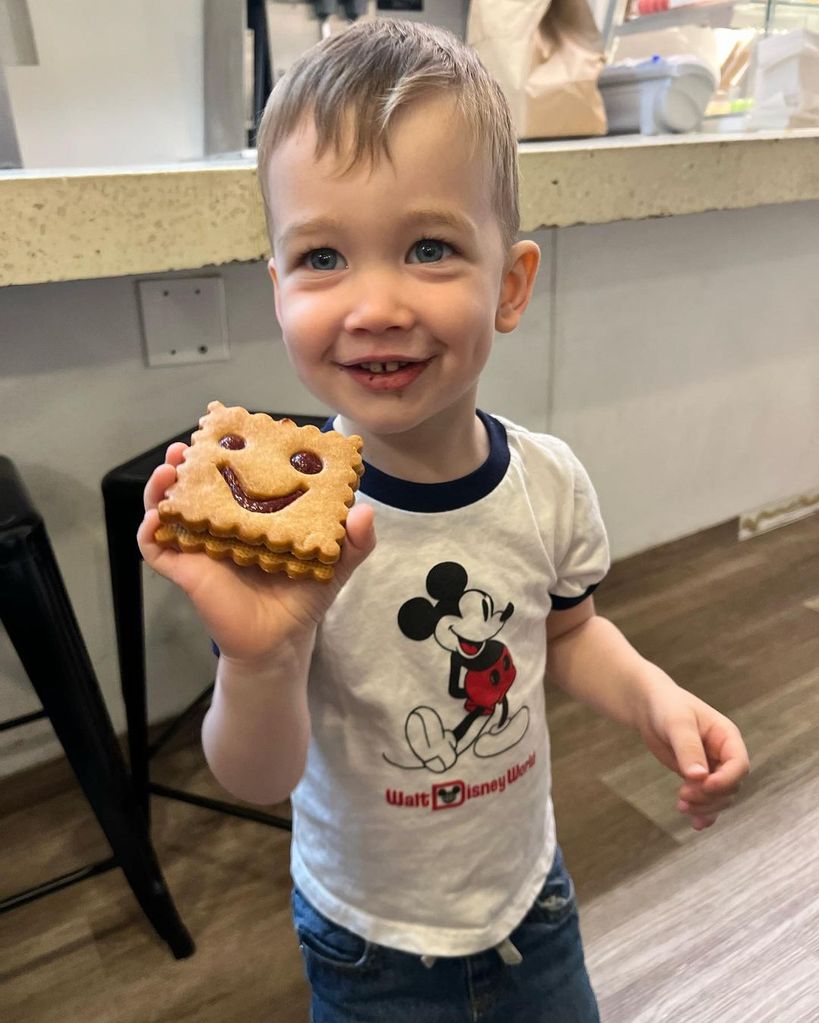 Wyatt smiling while stood in a kitchen holding a cookie