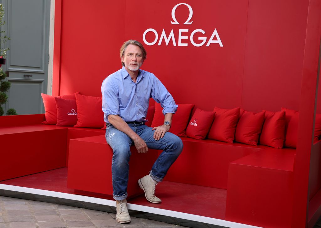 daniel craig posing on red stool with hand on knee 