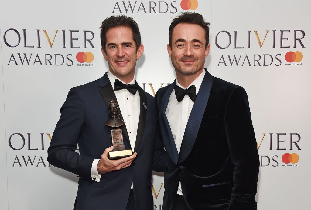 two men posing in tuxedos