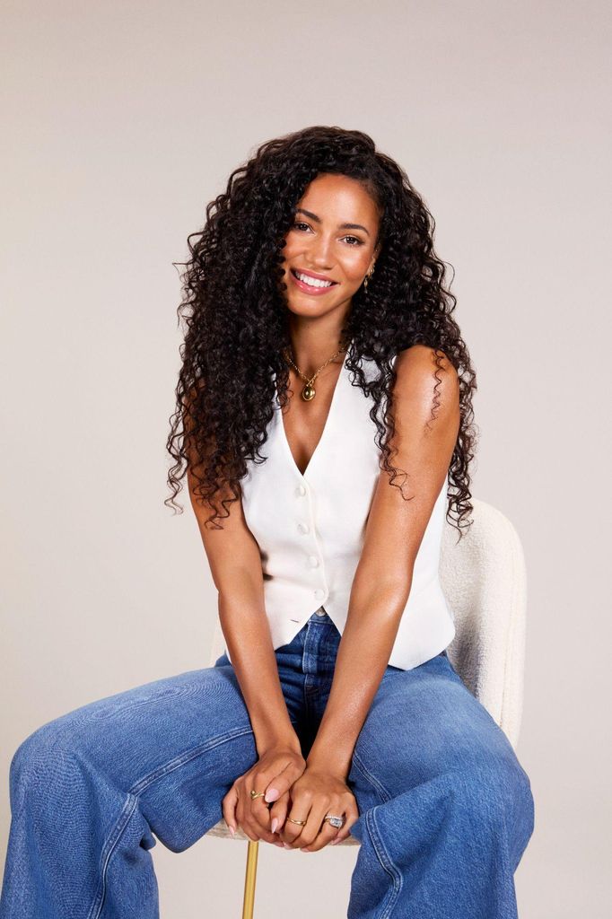 Vick Hope sitting on a chair in a white waistcoat