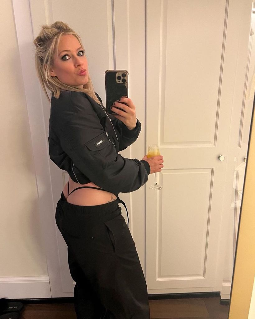 Avril Lavigne wearing low rise trousers and a G-string with a cropped black jacket in a mirror selfie