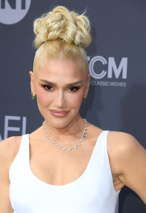 Gwen Stefani smiling on the red carpet in a white top