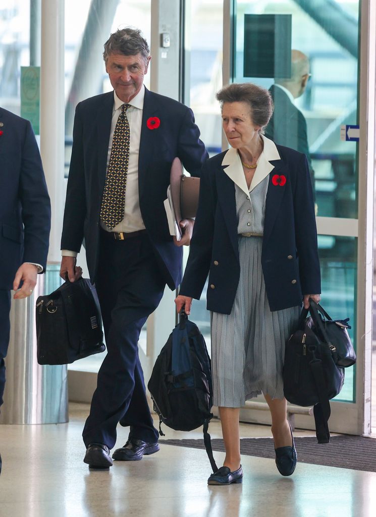 Princess Anne in airport in checked dress beside husband