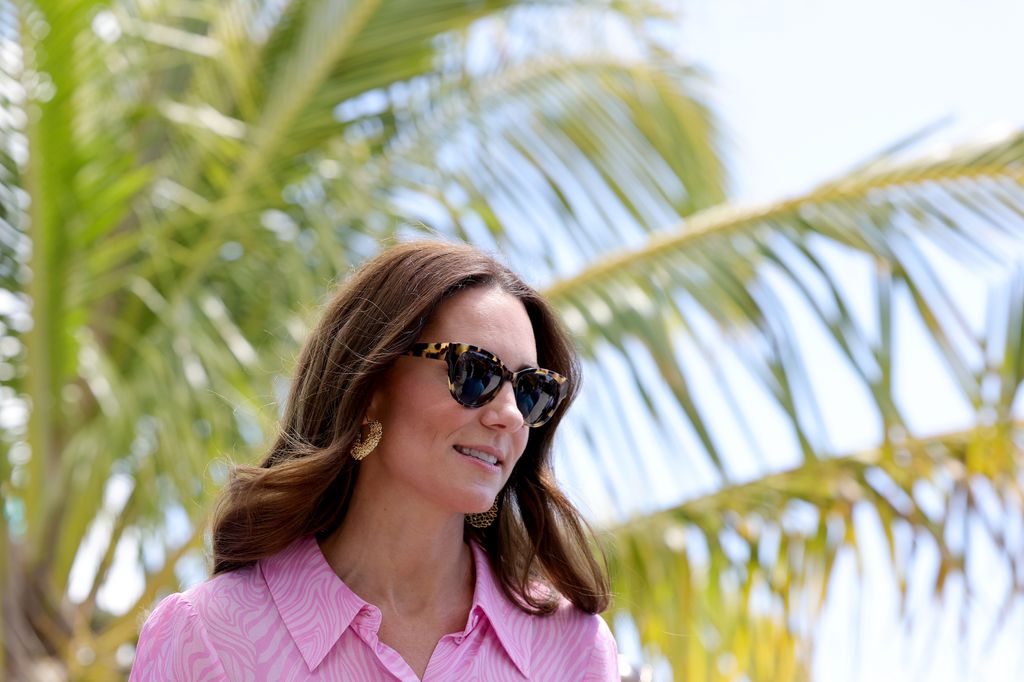 kate wearing sunglasses next to palm tree 