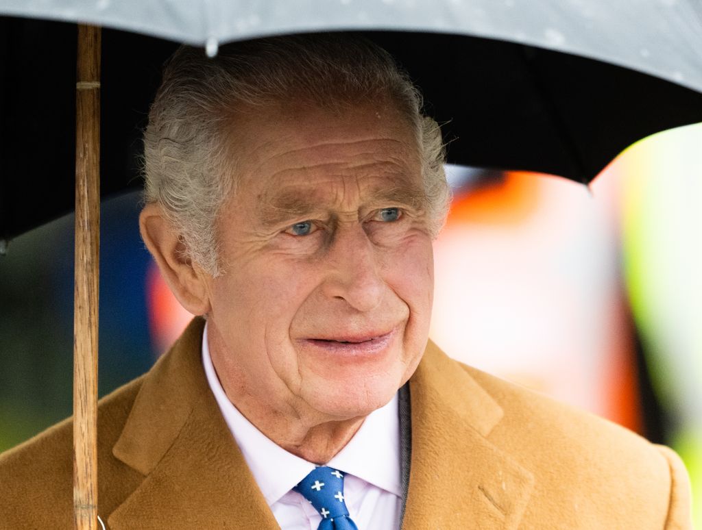 King Charles stands under umbrella